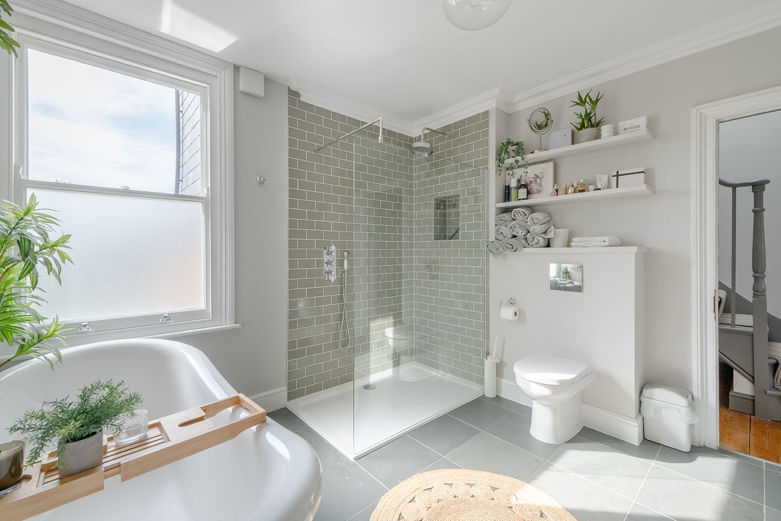 a bathroom photo from a property photography series, natural colours, bright and modern design space, light grey walls, light green tiles, showing the shower, toilet and partial bathtub
