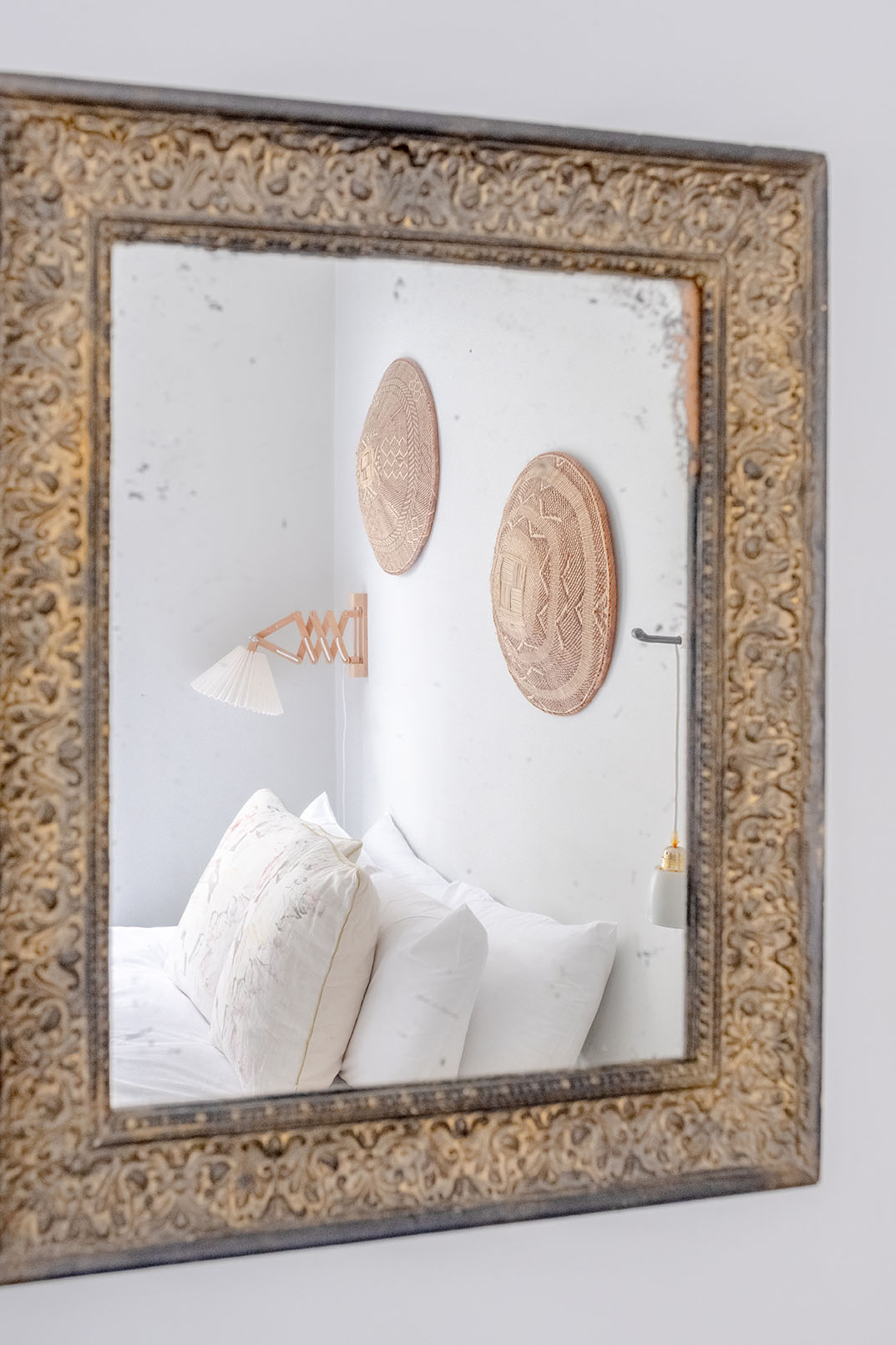 Reflection of a double bed with white linens and decorative items on the wall, shot for property photography.