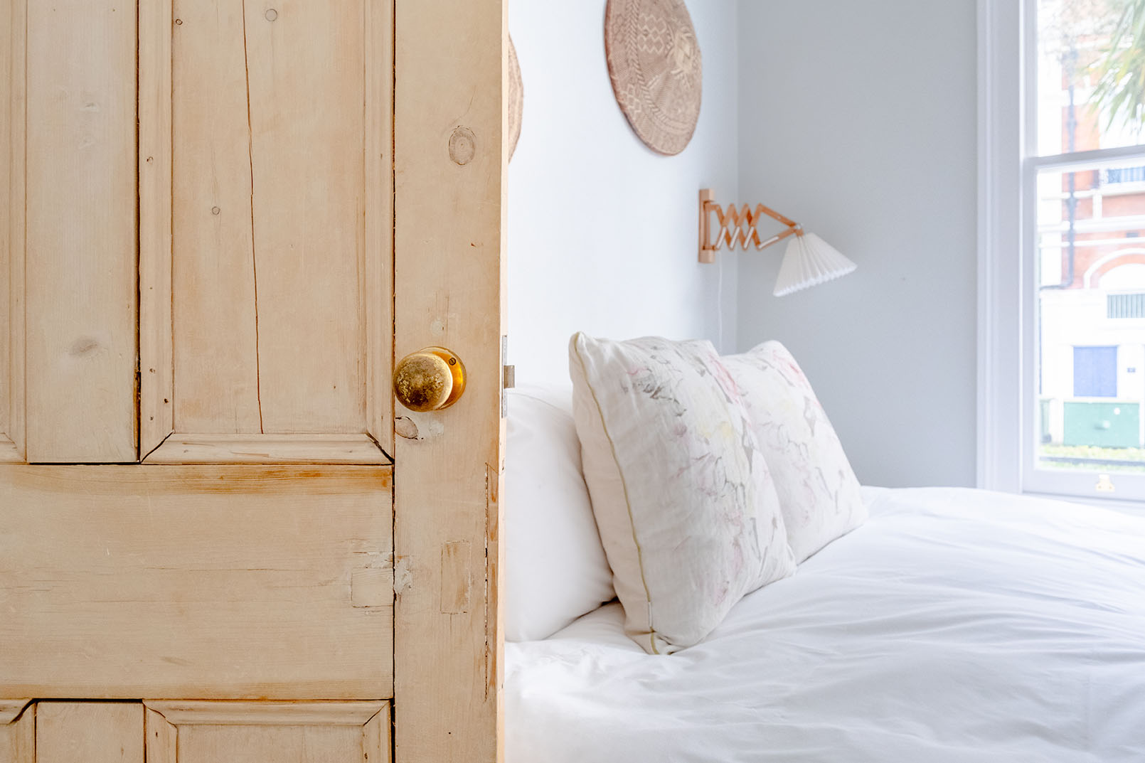 Detail of a bedroom for property photography, a wooden door close up shot, a double bed seen on the background with decorative cushions