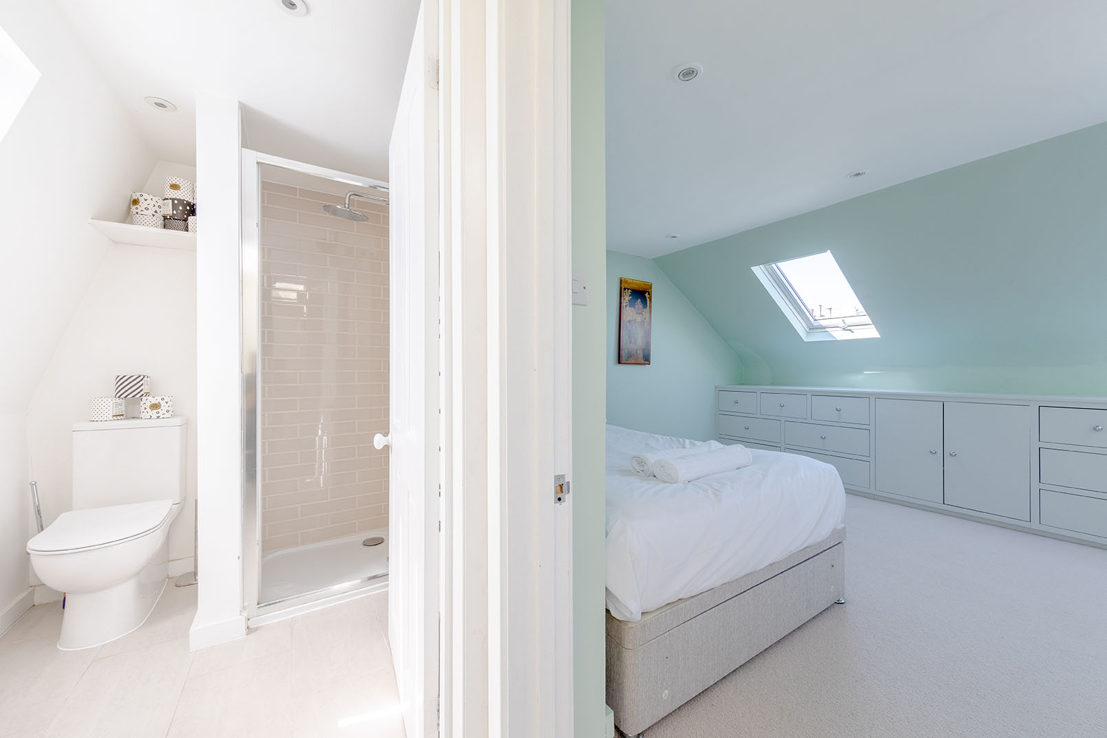 a bright property photo showcasing the connection between a white bathroom with shower and a bedroom