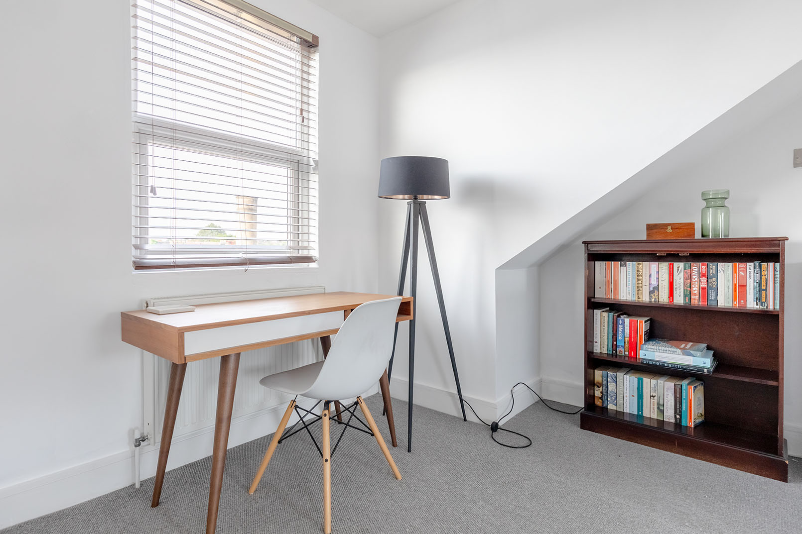 A bright, modern design study space in an attic room with a bookshelf, clean and neat room.