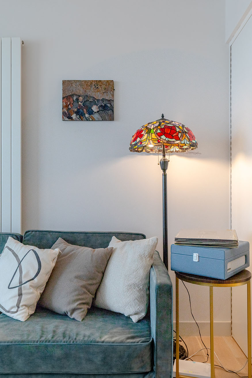 A detail photo for Airbnb listing framing the corner of a sofa and a coloured glass standing light