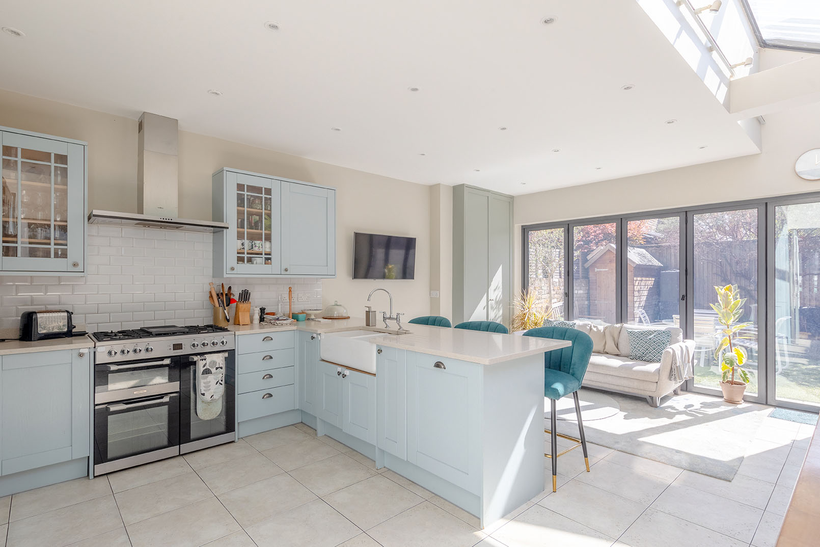 An open plan large kitchen with light blue cupboards, angle looking towards the living room, showing the connection for letting property photography.