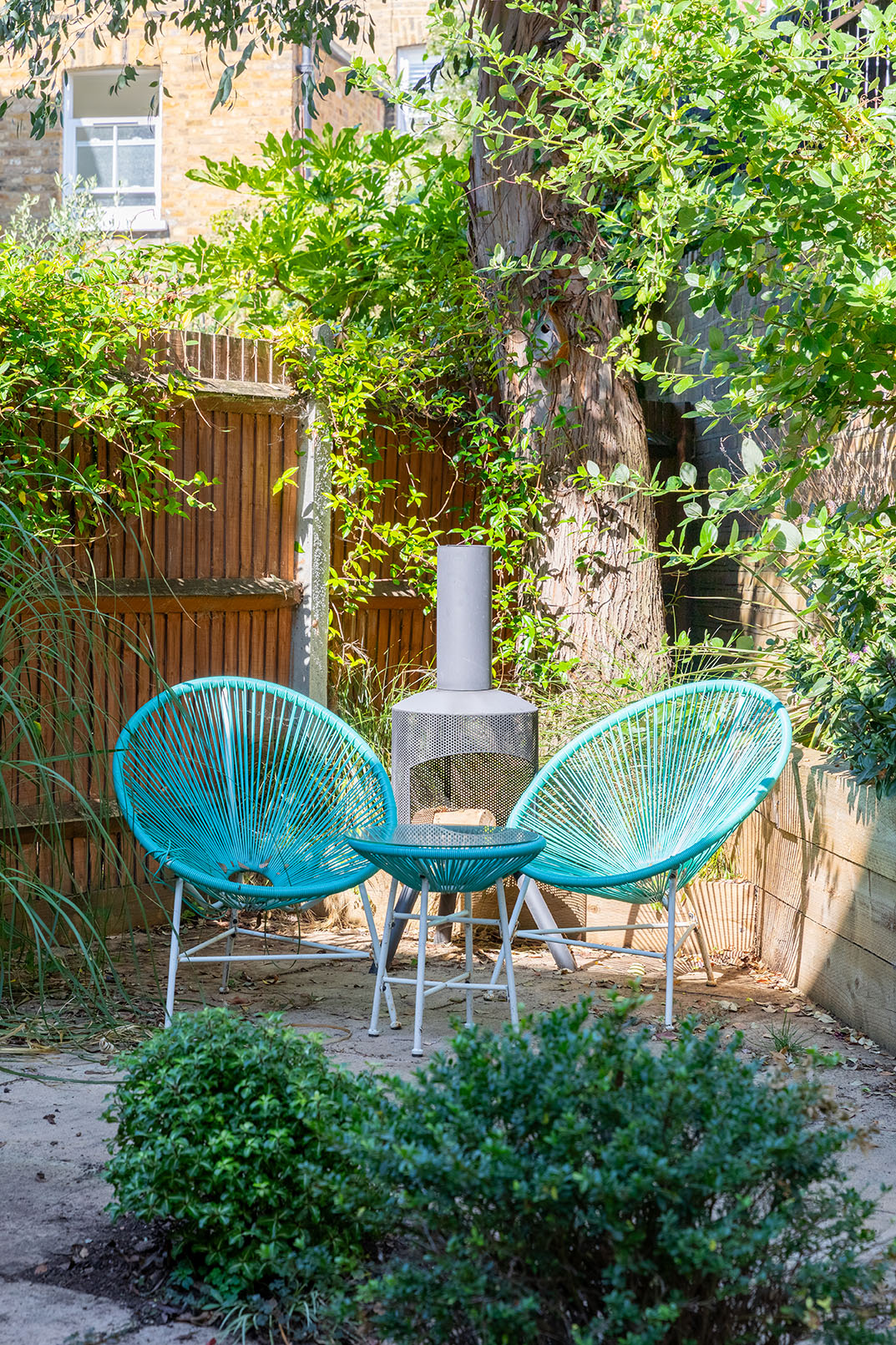 two green round metal chairs in a garden on a nice, sunny day.