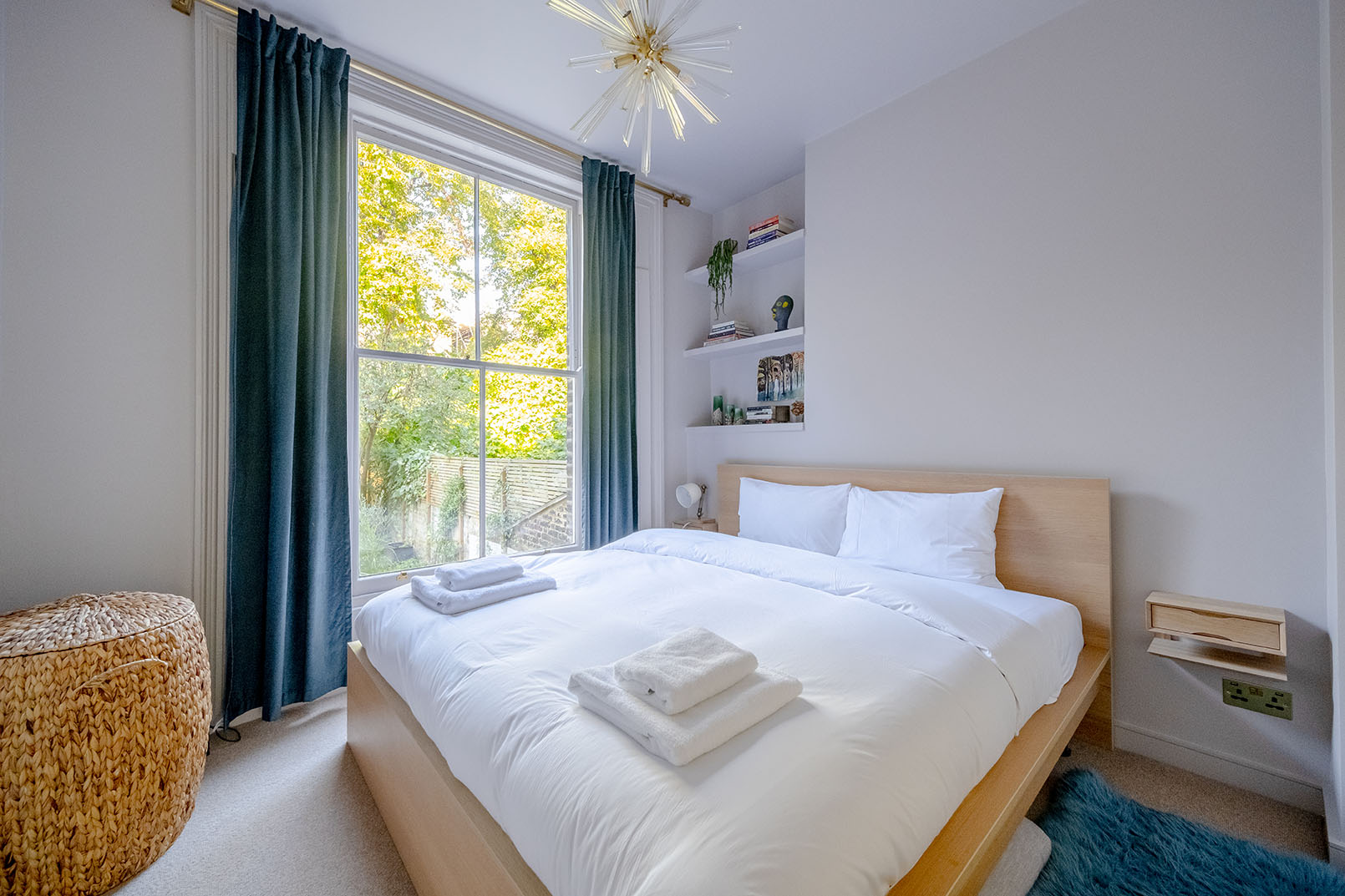 Cross angle image of a bedroom captured by a professional property photographer, white walls, white linens and a large window.
