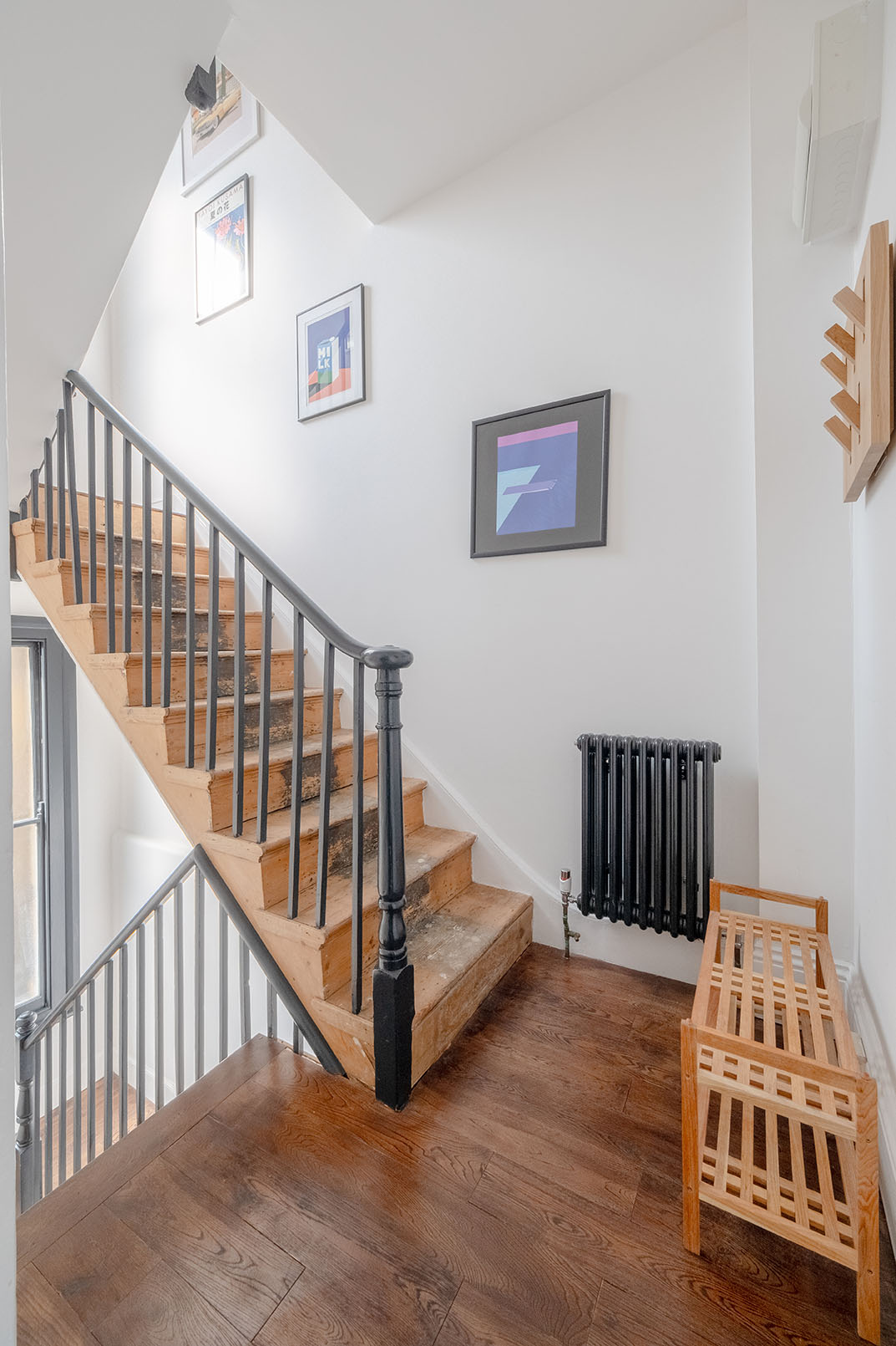 A natural wooden stair with a black painted wooden railing and banister.