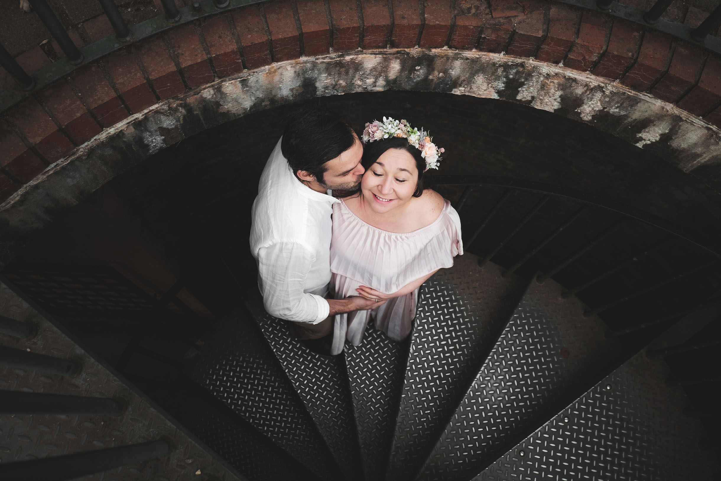 A couple man and woman standing on a metal stairs, captured from high angle for maternity family portrait phtography.