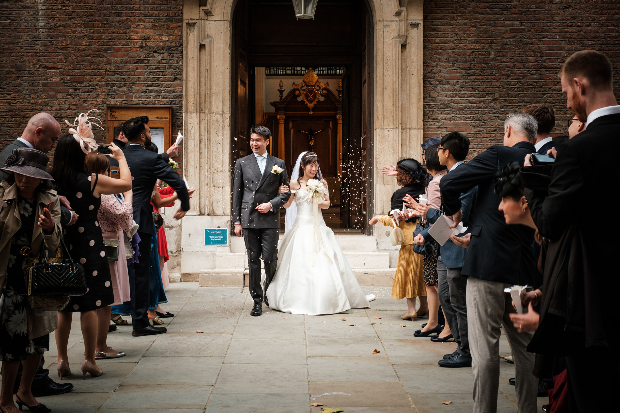 newly wed couple getting out of the church, meeting their friends and family members, celebrating and walking amongst them, wedding photography image.