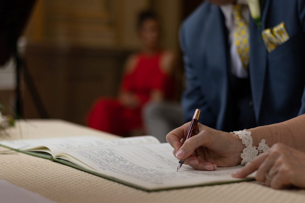 A bride signing the wedding book at the official ceremony, captured by wedding photographer.