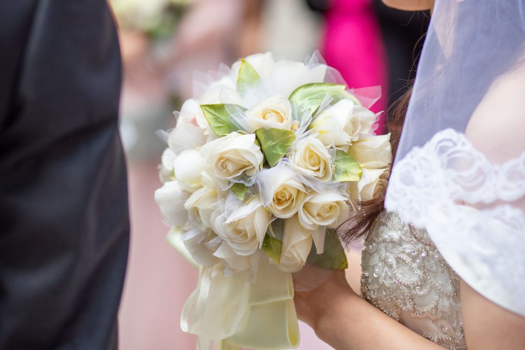 A bridal bouquet with white roses, bride is holding it, captured by wedding photographer.